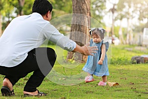 Daughter walking with dad playing in the park.