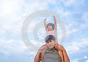 The daughter was riding on her father`s back, raising her hands to the beautiful fluffy clouds. The two looked very happy with