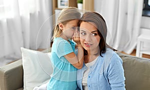 Daughter whispering secret to mother at home