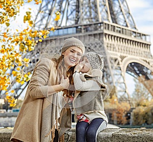Daughter whispering something to mother near Eiffel tower