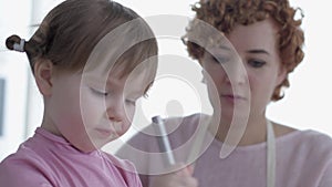 Daughter whispers to mom in the ear secrets while sitting in the kitchen for cooking