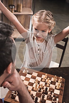 daughter winning chess game while playing with her father