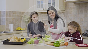 Daughters helps their mother to cook salad