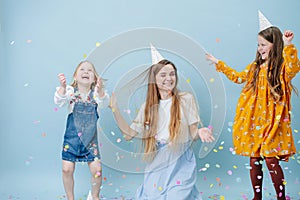 Daughters hugging their mother, all in party cones over blue