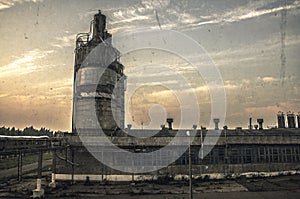 Dawn at an abandoned factory, housing with pipes, wires and industrial. In the sky, the dawn