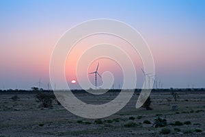 Dawn light in desert sky with Electrical power generating wind mills producing alterative eco friendly green energy for