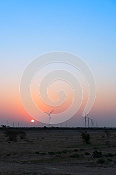 Dawn light in desert sky with Electrical power generating wind mills producing alterative eco friendly green energy for