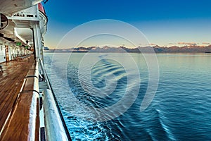 Dawn light on mountains and cruise ship Port side ocean ripples, Alaska, USA.