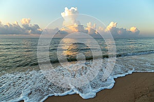 Dawn on the sea beach, mirror reflection of clouds on the water