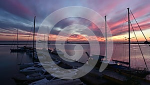 Dawn in the seaport. Boats and yachts sway on the waves at the pier, a large cargo ship swims out of the port