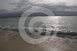 Dawn with stormy sky over the silver ocean. Lone fisherman boat in the water.