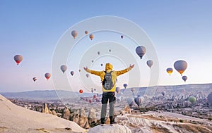 At dawn a tourist with a backpack on the background of soaring hot air balloons in Cappadocia, Turkey, concept achievement, team,