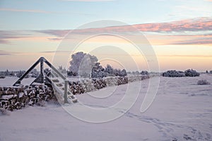 Dawn at a winterland with a stile by stone wall