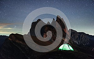 Dawned sun. Night photo of Seceda dolomites mountains. Tourists resting in the green tent