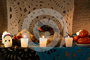 Day of the Dead altar with skulls, candles, molcajete sauce, tomato, bread of the dead and papel picado