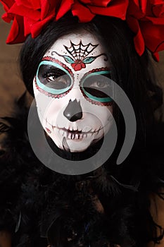 Day of the dead. Halloween. Young woman in day of the dead mask skull face art and rose. Dark background.