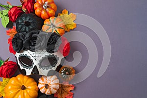 Day of the dead Mexican and Halloween holiday concept. Sugar skull mask, pumpkin and party decorations on purple background. Top