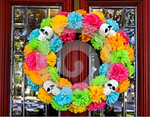 Day of the Dead wreath on door with tree and neighborhood reflected in beveled glass window