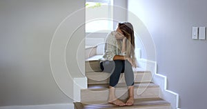 A day for despair. 4k video footage of a young woman looking sad while sitting on her stairs.