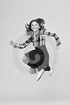 Day full of fun. Happy child enjoy happiness. Energetic girl in midair yellow background. Childhood and happiness