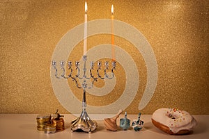 Day 1 of jewish holiday Hanukkah with traditional chandelier menorah, spinning top toys dreidels and a doughnut and ch