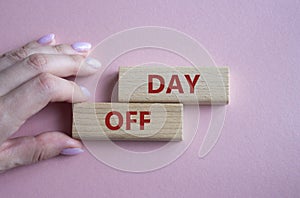 Day off symbol. Concept word Day off on wooden blocks. Businessman hand. Beautiful pink background. Business and Day off concept.