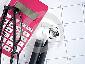 Day of payment for rent or loan. Calendar,pen, calculator, glasses and icon home payment on calendar