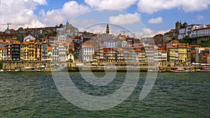 Day timelapse of Porto oldest district Ribeira, Douro River, Portugal. Clouds fly above medieval houses, tourist boats