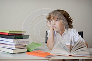 Daydreaming schoolboy sits at a school desk photo