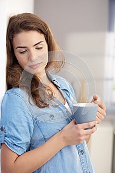 Daydreaming woman drinking tea at home