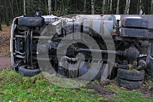 daylight. fall. A white truck with a trailer lies in a ditch turned over on its right side. Vehicle damage