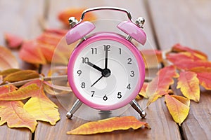 Daylight savings time, pink alarm clock on a wooden background