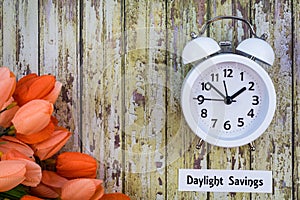 Daylight Savings Time Spring concept top down view with white clock and orange tulips