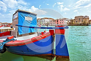 Daylight view to vibrant colorful blue and red boat parked in Venetian Lagoon