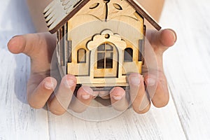 daylight. on a wooden background, in children& x27;s hands a toy house. Close-up