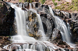 Daytime long exposure of Gooseberry Falls waterfalls at the state park in Minnesota in summer. Close up view