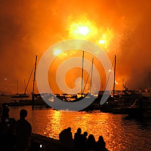 Dazzling fireworks orange dust over harbor landscape with people watching