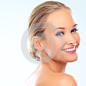 Dazzling smile. Studio shot of a beautiful young woman with perfect skin against a blue background.