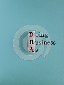 DBA-Doing Business As - acronym on wooden cubes on a blue background.