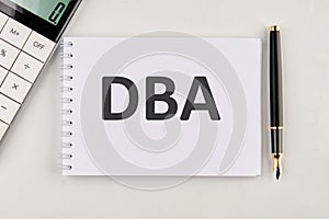 DBA the inscription on the notebook next to the calculator and pen