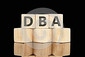 DBA text assembled from wooden cubes on a black background