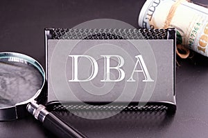 DBA text on the business card next to the money, a magnifying glass on a black background