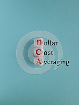 DCA (Dollar Cost Averaging) red words on a wooden cubes. Beautiful blue background.