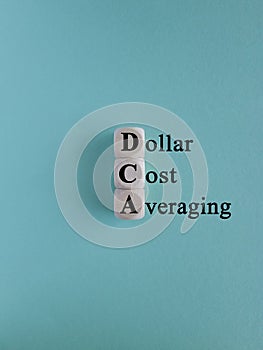 DCA (Dollar Cost Averaging) words on a wooden cubes. Blue background. Saving stock or savings on a monthly