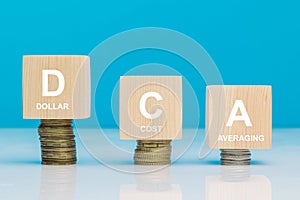 DCA word on a wooden cubes on coins in idea Dollar Cost Averaging investment strategy, Saving stock or savings on a monthly,