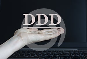 DDD - acronym on a woman`s hand against the background of a laptop