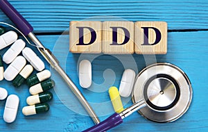 DDD - acronym on wooden cubes on a blue background with a stethoscope and tablets