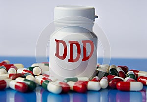 DDD - medical acronym on a white jar against the background of randomly scattered tablets