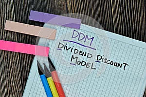 DDM - Dividend Discount Model write on a book isolated on Wooden Table