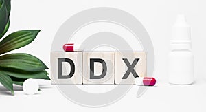ddx the word is written on wooden cubes,plant and red pills,on white background